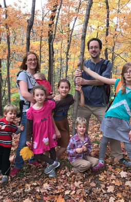 Jonathan Koudelka with his family in the woods with lots of fallen leaves