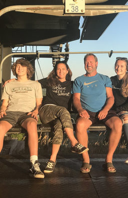 Brandi Kloostra smiling alongside her family on a chairlift