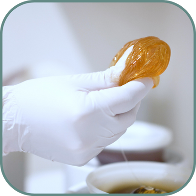 Close-up of a person holding a ball of sugar wax, ready for use in a hair removal treatment at a sugaring franchise.
