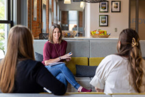 A business woman discussing how franchises work to two other women on a couch.