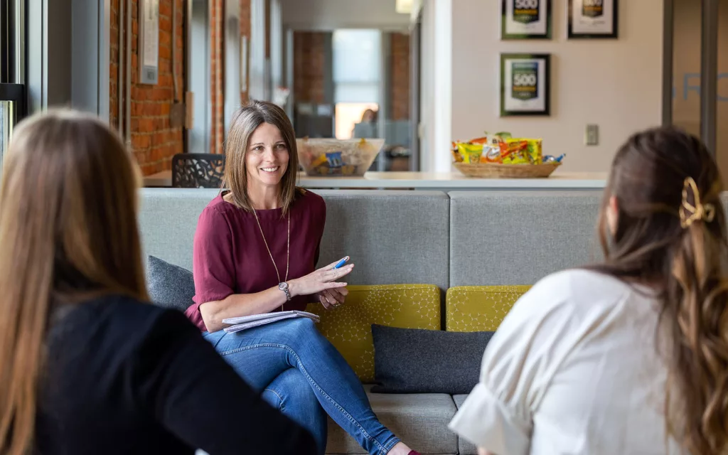 A group of professional women discussing how franchises work in an office