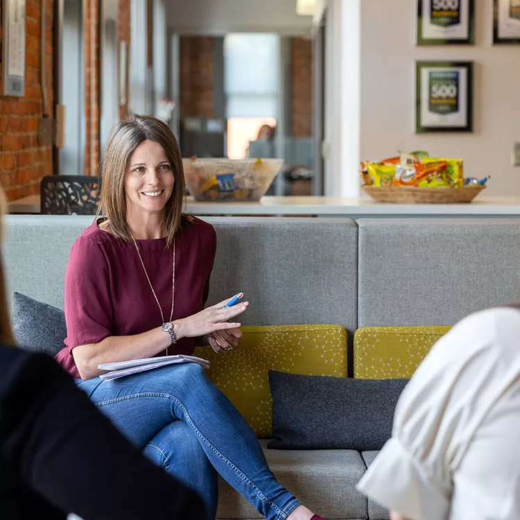 A group of professional women discussing how franchises work in an office